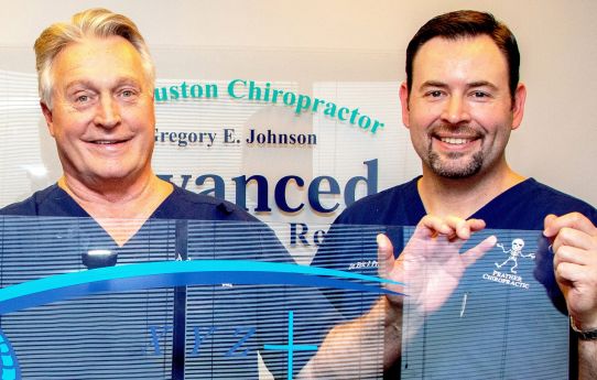Dr. Prather and another person in blue scrubs holding up a sheet of plexiglass.