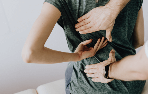 Person touching their back and a chiropractor's hands above and below their hand.