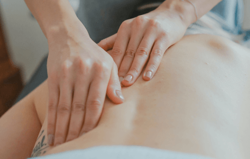 Chiropractor palpating a patient's bare back.