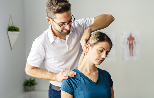Chiropractor standing behind a patient and stretching their neck.