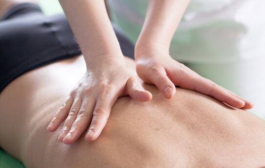 Stock photo of a chiropractor's hands on a person's back.